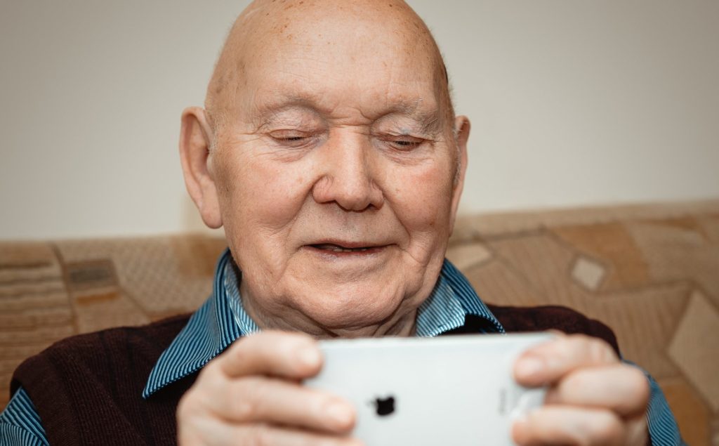 Socially isolated senior during COVID-19 pandemic using his phone for a video call with family