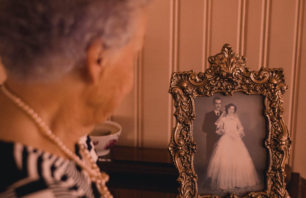 Socially isolated senior during COVID-19 pandemic reminiscing by looking at her wedding photo